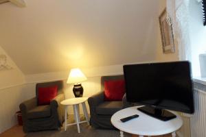 a living room with two chairs and a flat screen tv at Pension Lærkelill in Skovlund