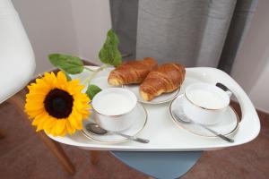 a tray with croissants and cups and a sunflower at B&B CA DEL SOLE in Serravalle Scrivia