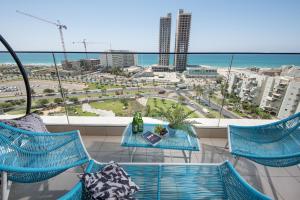 a balcony with blue chairs and a table with a view of the ocean at Bat Yam Luxery 5BR Sea View Suite in Bat Yam