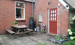 a picnic table in front of a brick building with a red door at Riley's cottage in Hemrik