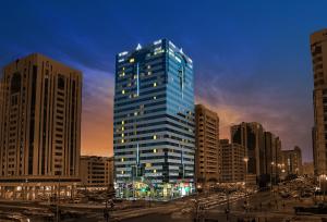 a tall blue building in a city at night at Al Maha Arjaan by Rotana in Abu Dhabi