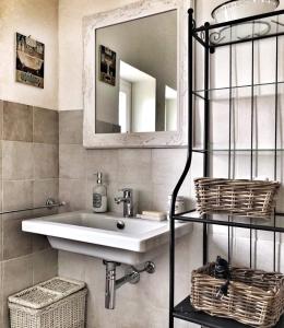 ein Badezimmer mit einem Waschbecken, einem Spiegel und Körben in der Unterkunft Noi Due Guest House - Fubine Monferrato in Fubine