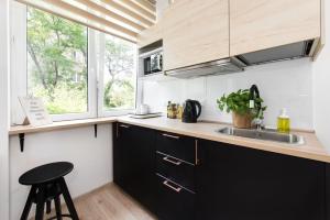 a kitchen with black cabinets and a sink at SuperApart Gagarina MiniStudio in Warsaw