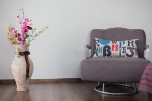 a vase of flowers sitting next to a chair at Aparthotel Laura in Cluj-Napoca