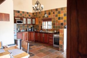una cocina con armarios de madera y azulejos en la pared en Milorho Lodge, en Rietfontein