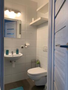 a white bathroom with a toilet and a sink at Pokoje gościnne Lisa in Władysławowo