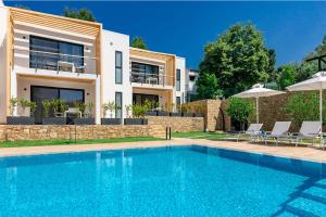 a villa with a swimming pool in front of a house at EOS Luxury Suites in Kriopigi