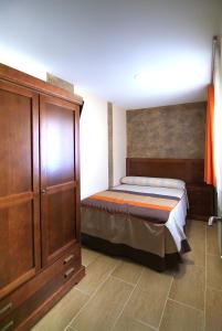 1 dormitorio con 1 cama y armario de madera en Apartahotel La Corrala en San Martín de Moncayo