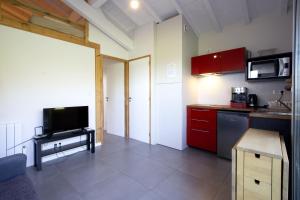 a kitchen with red cabinets and a flat screen tv at PURA VIDA # meublé plein de charme océan montagne in Villefranque