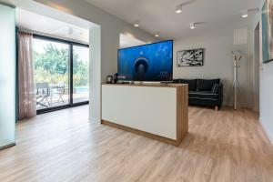 a living room with a large tv and a white counter at EOS Luxury Suites in Kriopigi