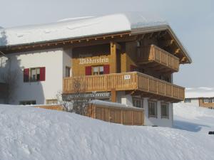 ein großes Gebäude mit einer Terrasse im Schnee in der Unterkunft Pension Widderstein in Lech am Arlberg