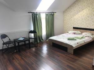 ein Schlafzimmer mit einem Bett, einem Tisch und einem Stuhl in der Unterkunft Casa de vacanta Madalina in Novaci-Străini
