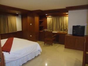 1 dormitorio con 1 cama, escritorio y TV en Tanawit Hotel & Spa, en Hua Hin