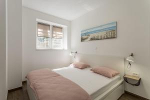 ein weißes Schlafzimmer mit einem Bett mit rosa Kissen in der Unterkunft Apartment Lana in Split