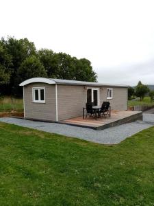 un petit bâtiment avec une table de pique-nique sur une terrasse dans l'établissement La Roulotte Julyana, à Vielsalm