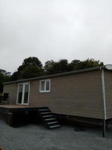 a tiny house with a porch and a staircase at La Roulotte Julyana in Vielsalm