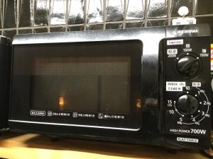 a black microwave oven sitting on top of a table at Gion Kyoto Miyagawacyo Guesthouse HANAKANZASHI in Kyoto