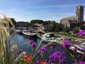 a group of boats docked in a harbor with purple flowers at La bigoudène in Wambrechies