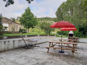 - une table de pique-nique avec un parasol rouge et un banc dans l'établissement Casa dos Namorados, à Vale de Cambra