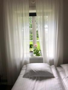 a bedroom with a bed and a window with white curtains at Gårdshotellet in Ystad