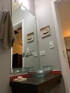 baño con lavabo de cristal y espejo en Casa com Piscina Aquecida Privativa en Juquei
