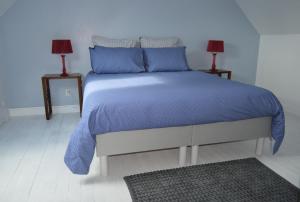 a bedroom with a bed with blue sheets and two lamps at Ty Mamm Gozh in Plonévez-Porzay
