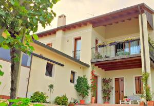 una casa con un balcone e un albero di Le Vigne di Annalisa Sweet Relax Rooms in Unesco Prosecco D.o.c.g. a Farra di Soligo