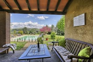 un patio con mesa, bancos y piscina en Appartamento Girasole - Agriturismo le Selvole, en Pomarance