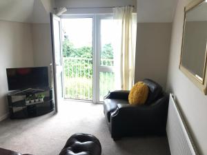 ein Wohnzimmer mit einem schwarzen Ledersofa und einem TV in der Unterkunft Weston Shore in Southampton