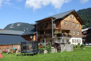 ein großes Haus mit einem Spielplatz davor in der Unterkunft Pension Haus Romy in Schoppernau