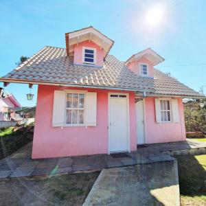 a pink house with white windows and a roof at Pousada Canto de Pássaros in Painel
