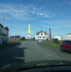 a yellow arrow on a road with a lighthouse at Apt 201 - Andenes Whale Safari Apartments in Andenes