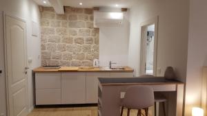 a kitchen with a sink and a counter with chairs at Apartments Milion in Korčula