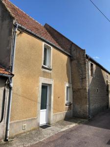 um velho edifício de tijolos com uma porta branca em GITE BORD DE MER em Bernières-sur-Mer
