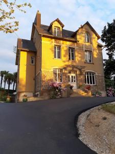 una casa amarilla con una entrada delante de ella en La Garenne, en Bricquebec