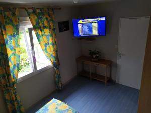 Habitación con ventana y TV en la pared. en Chambres Le Mans 24 heures, en Arnage