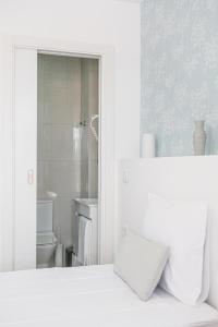 a white bedroom with a white bed and a bathroom at 4U Lisbon Suites & Guesthouse VII Airport in Lisbon