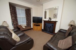 a living room with two leather couches and a television at Jo's House in Walsall