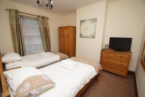 two beds in a room with a tv on a dresser at Jo's House in Walsall