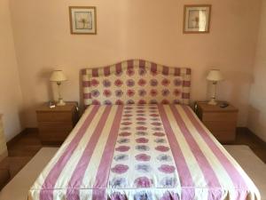 a bedroom with a bed with a striped bedspread and two lamps at Atlantic Waves Accommodation in Carcavelos