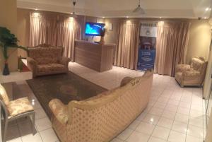 a living room with chairs and a tv and a couch at Bridgeville Guest House( Pty) Ltd in Gaborone