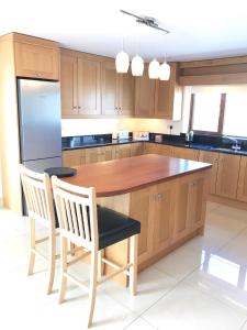 a kitchen with a wooden island with chairs and a refrigerator at Rannagh View in Liscannor
