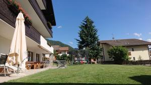 a lawn with an umbrella next to a building at Pension Tirol in San Valentino alla Muta