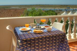 a table with food and drinks on a balcony at Casa da Ria Formosa in Cabanas de Tavira