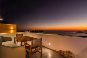 a balcony with a table and a view of the ocean at Caldera Stories private suites in Megalochori