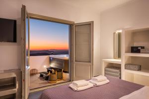 a room with a bed with a view of a balcony at Caldera Stories private suites in Megalochori