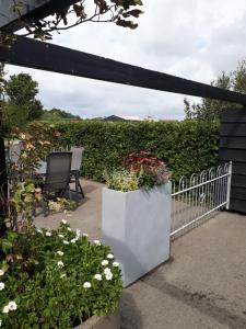 a patio with a bench and flowers and a fence at de Paardekracht in Serooskerke