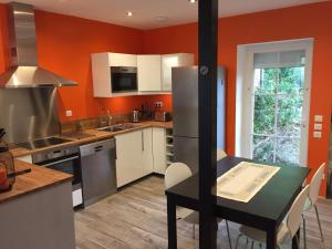 a kitchen with orange walls and a table and a counter at L appartement du parc in Villemur-sur-Tarn