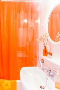 a bathroom with an orange shower curtain and a sink at SOL NAIXENT in Fornells