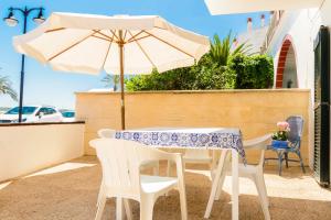 uma mesa e cadeiras com um guarda-sol num pátio em SOL NAIXENT em Fornells